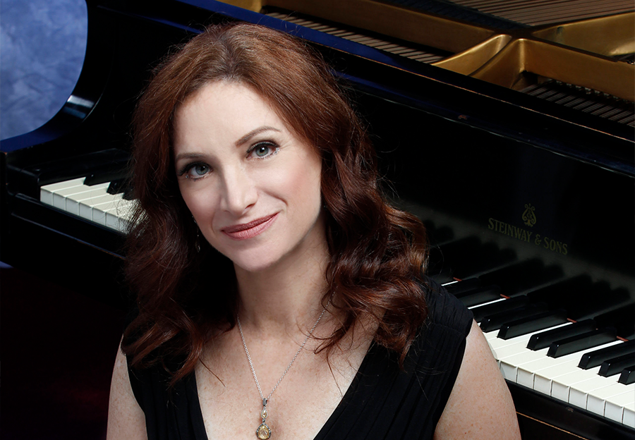 lady with brown hair with a piano behind her