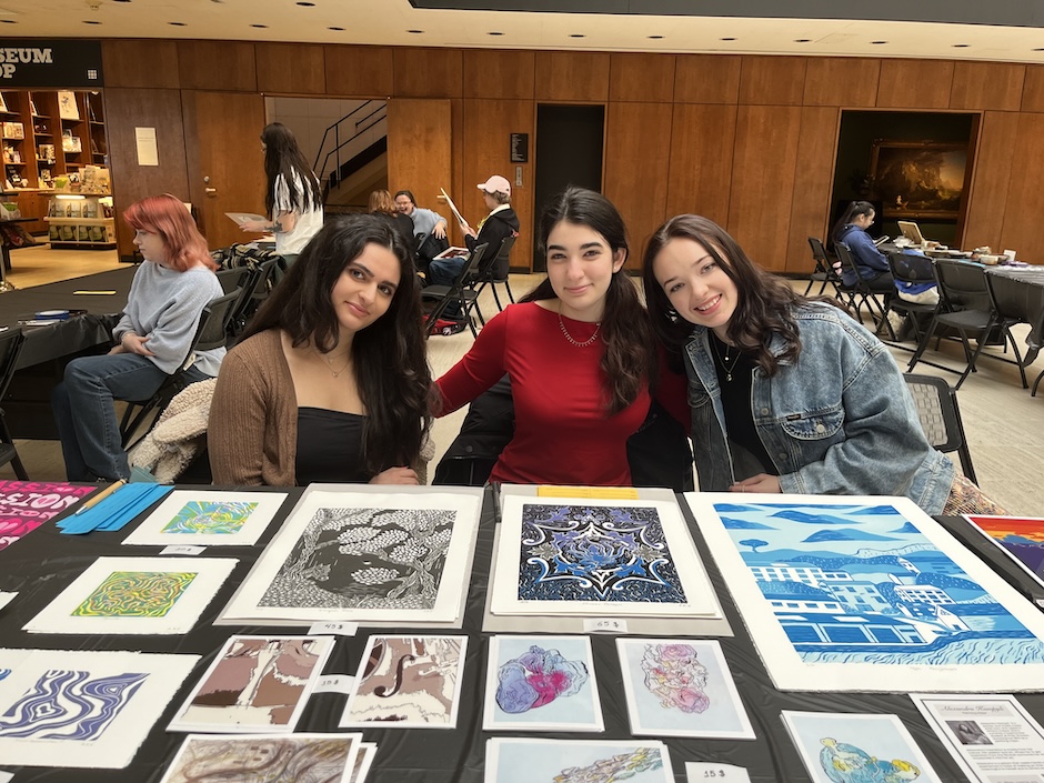 students sitting at a table selling art