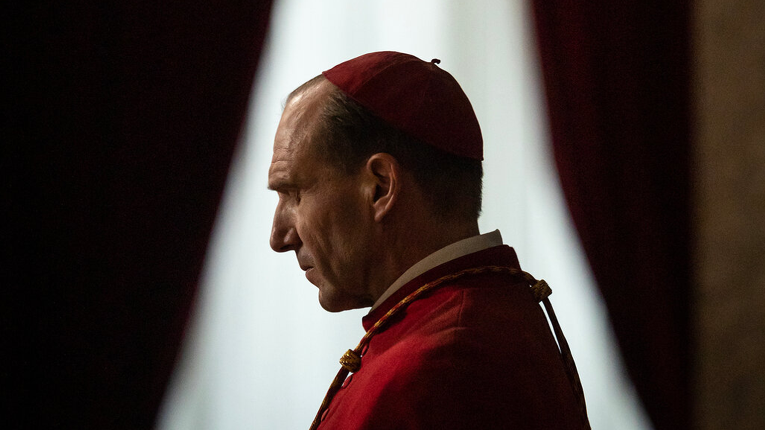 A bald man who looks like a priest staring with head down by 15 degrees.