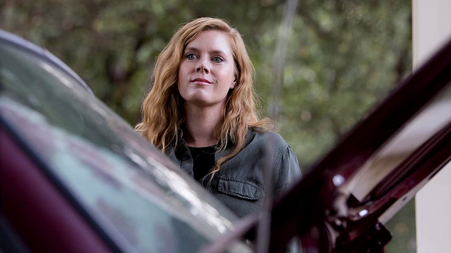 Orange haired woman standing by her car with a big smile.