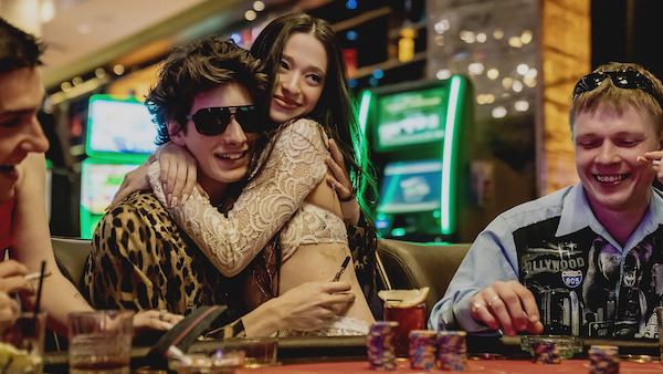 A girl sitting on her partner's lap in a casino with a big smile. there is a blonde man next to them.