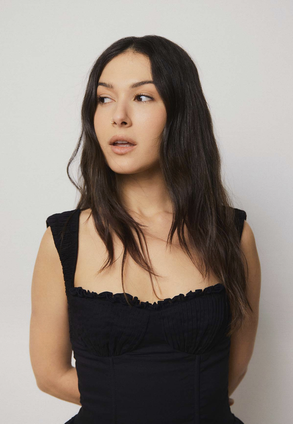 nella in black strap shirt with long brown hair down against a white background.